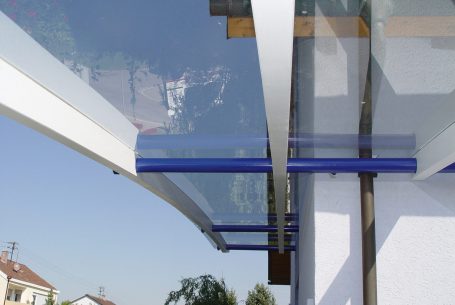 Glasüberdachung mit blauen Akzenten und weißen Strukturen an einem  Gebäude.
